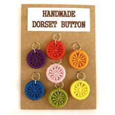 six handmade crochet buttons in different colors on a piece of brown paper