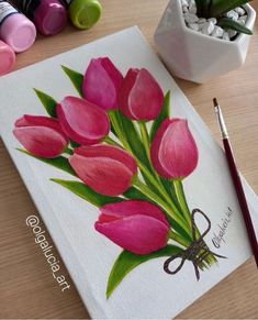 a painting of pink tulips on a white canvas next to some crayons