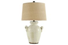 a white ceramic lamp with a beige shade