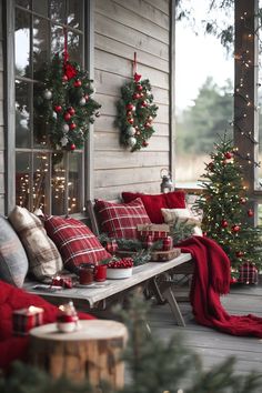 a porch decorated for christmas with red and white plaid pillows, wreaths and decorations