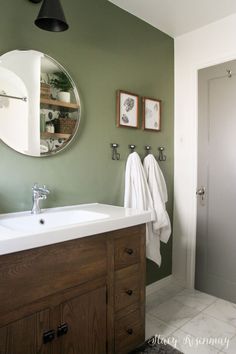 a bathroom with green walls and white counter tops, two mirrors on the wall above the sink