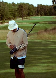 a man standing on top of a lush green field holding a golf ball and club