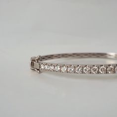 This stunning diamond bangle is a classic design that can be worn for any events. Featuring over a total of approximately 2 carat natural white diamonds framed in 14K and 18K solid gold. The bangle has a slightly tapered band creating a feminine look. Put together with a box clasps and a safety hinge. Handcrafted in 14K Yellow gold, rose gold and white gold. Model is wearing 6.5" bracelet. 14K or 18K solid gold 25 Natural white brilliant cut diamonds. SI clarity GH color, Approx 2 ct total carat Elegant Oval Bangle With Single Cut Diamonds, Platinum Bangle Diamond Bracelet, Platinum Bangle Diamond Bracelet With Diamond Cut, Platinum Diamond Cut Bangle Bracelet, Wedding Platinum Diamond Bracelet With Brilliant Cut, Formal Oval Bangle With Diamond Accents, Formal Diamond Bangle, Dazzling Platinum Diamond Bracelet Hand Set, Dazzling Hand Set Platinum Diamond Bracelet