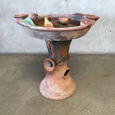 an old vase is sitting on the floor next to a concrete wall and cement floor