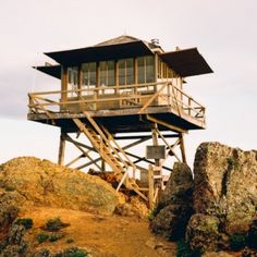 a tall wooden tower sitting on top of a rocky hillside next to a cliff side