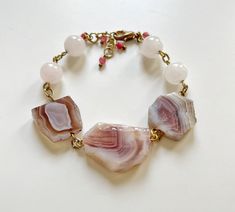 Welcome to our enchanting collection of handcrafted gemstone bracelets, where elegance meets the healing power of nature's most precious gems. Our Pink Quartz and Agate beaded bracelet is a stunning embodiment of beauty and positive energy. Indulge yourself or surprise a loved one with this exquisite pink quartz bracelet, a symbol of love, compassion, and emotional healing. Crafted with delicate precision, each pink quartz crystal bead radiates soft, soothing energies, offering comfort and tranquility to your everyday life. The gentle, blushing hues of Pink Agate in this bracelet add a touch of sophistication and a dash of serenity. Known for its stabilizing properties, pink agate enhances inner strength, balancing the mind, body, and spirit. It's a stone that promotes harmony and a sense Pink Agate Crystal Bracelet As A Gift, Pink Spiritual Crystal Bracelet With Natural Stones, Spiritual Pink Crystal Bracelet With Natural Stones, Pink Agate Spiritual Bracelets, Pink Agate Beaded Bracelets With Natural Stones, Pink Healing Bracelets With Natural Stones, Healing Pink Bracelets With Natural Stones, Handmade Pink Agate Bracelets, Bohemian Rose Quartz Crystal Bracelet With Natural Stones