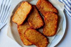 some fried food on a white plate with silverware