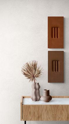 two vases are sitting on a table next to a wall with three different shapes