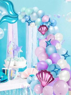 a table topped with lots of balloons and starfishs next to a blue wall