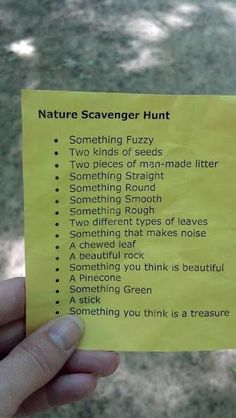 a person holding up a yellow paper with some writing on it that says nature scavenger hunt