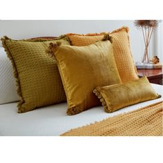 a bed topped with lots of yellow pillows