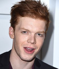 a close up of a person wearing a suit and tie with a smile on his face