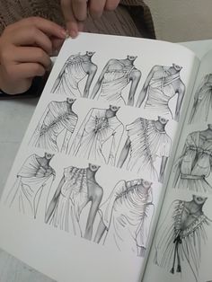 a person is holding an open book with drawings on it and looking at the pages