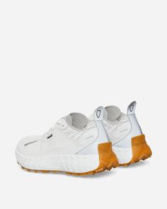 a pair of white sneakers with orange soles