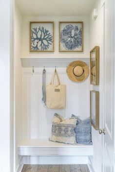 a white bench with two pictures on the wall and a hat hanging from it's hooks