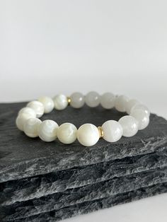 💎 MATERIAL DETAILS ○ 10mm Mother of Pearl Shell → soothing, stimulates adaptability, intuition, and imagination  ○ 10mm White Jade → abundance, prosperity, detox, calmness, and love ○ 6mm 18k gold plated spacers ○ High quality, resistant, and flexible elastic cord (double-corded) 💯 QUALITY & CRAFTSMANSHIP ○ Materials are handpicked, inspected, and handled with the utmost quality and care ○ Double-corded with high quality elastic cord - this means our bracelets have 2x the durability of other s Elegant Moonstone Bracelets For Meditation, White Gemstone Beads Bracelet As Gift, White Beaded Gemstone Bracelets For Everyday, Everyday White Beaded Gemstone Bracelets, Elegant White Crystal Bracelet For Healing, Minimalist White Gemstone Bracelet, White Moonstone Bracelets For Everyday, White Moonstone Bracelet For Everyday, White Gemstone Beaded Bracelets For Meditation