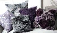 four decorative pillows sitting on top of a couch next to a vase filled with flowers