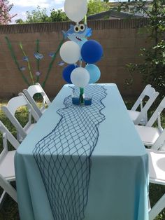 a table topped with blue and white balloons