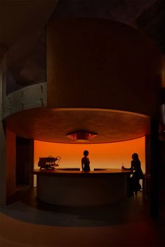 two people sitting at a counter in front of an orange lit room with circular lights