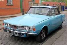 an old blue car is parked on the street