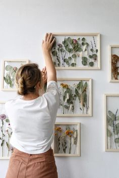 a woman is placing flowers on the wall with her hands and touching them against the wall