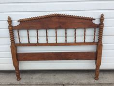 an old wooden bed frame sitting in front of a garage door