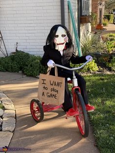 a creepy doll riding a tricycle with a bag on the handlebars that says i want to play a game