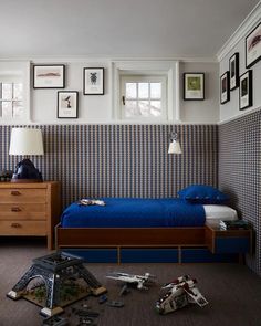 a blue bed in a bedroom with pictures on the wall above it and other items scattered about