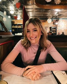 a woman sitting at a table with a menu in front of her smiling for the camera