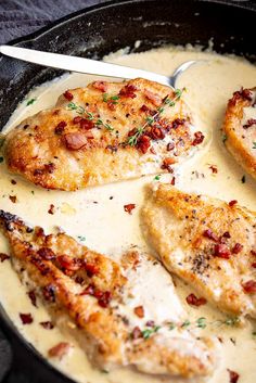 some chicken is cooking in a skillet with white sauce and garnished with parsley