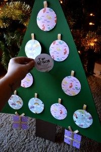 a hand is holding up a christmas tree made out of paper plates and clothes pins