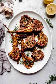 grilled lamb chops on a white plate with lemon wedges