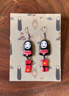 a pair of cartoon character earrings on top of a piece of paper with a wooden background