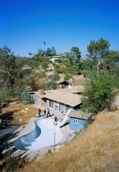 an aerial view of a house with a pool in the foreground and people walking around