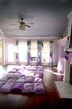 a living room filled with lots of purple furniture and decor on top of a hard wood floor