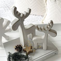 a white bookend with a reindeer on top of it next to a pine cone