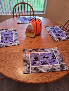 a wooden table topped with place mats and pumpkins