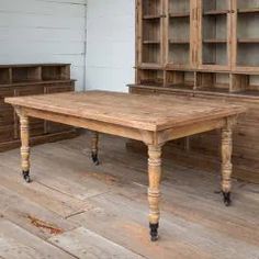 a wooden table sitting on top of a hard wood floor next to a book shelf