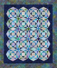 a blue and green quilt with many different shapes on the front, one in the middle