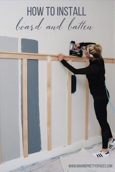 a woman is painting the walls with blue and gray paint in her living room, using a power drill