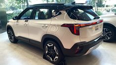 the rear end of a white suv in a showroom with two other cars behind it