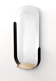 a mirror mounted to the side of a wall next to a white wall with a black frame