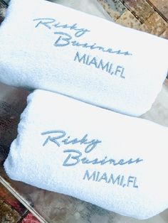 two white towels with names on them sitting on a towel rack next to each other