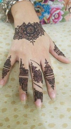 a woman's hand with henna tattoos on it and flowers in the background