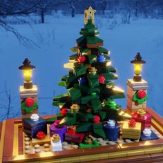 a lego lit christmas tree on top of a table in front of snow covered ground