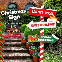 a christmas sign in front of a brick building with flowers and potted plants on the steps