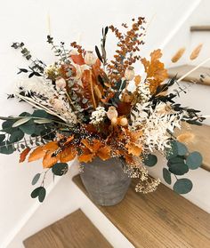 a vase filled with lots of flowers on top of a wooden stair case next to a hand rail