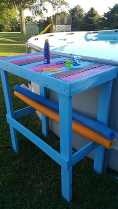 a blue table sitting in the grass next to a swimming pool