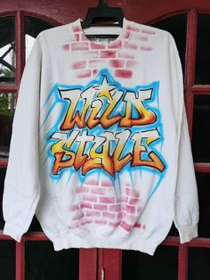 "Please read all description carefully before buying. If you have any questions feel free to ask. Vintage 1990's Wild Style Hip Hop Movie T-shirt Colour : White Size on tag : M Brand : Gildan Condition : Good condition. MEASUREMENT Armpit to armpit : 22\" Shoulder to bottom hem : 23\" PLEASE CHECK ACTUAL SIZE CAREFULLY, NO RETURNS OR COMPLAINT FOR WRONG SIZE ACTUAL. ACCEPT PAYPAL ONLY. Shipping cost is $28 via DHL Express wordwide shipping. Transit time can take 3-5 business days to reach destin Oversized Throwback Tops For Streetwear, Cotton Tops With Custom Artwork For Streetwear, Retro Graffiti Print Tops For Streetwear, 90s Style Graphic Print Sweatshirt For Fans, 90s Graphic Print Sweatshirt For Fans, Throwback Crew Neck Top For Streetwear, Throwback Long Sleeve T-shirt For Streetwear, Cotton Graffiti Print Sweatshirt For Streetwear, Cotton Sweatshirt With Graffiti Print For Streetwear