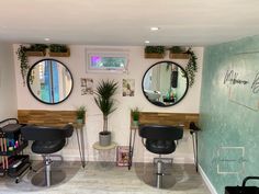 a hair salon with mirrors and chairs in front of the wall, two planters on each side